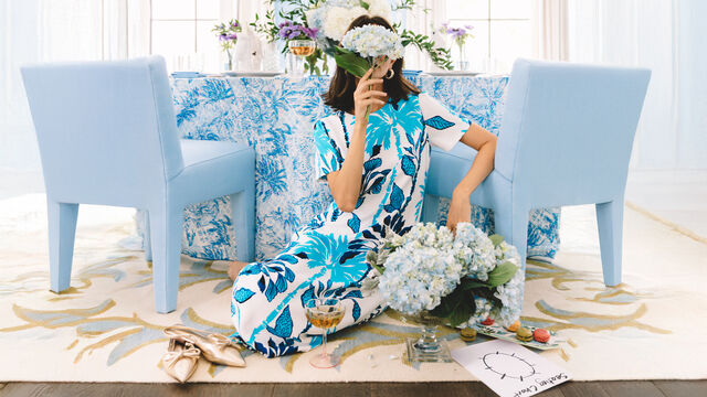 Woman in blue printed dress holding flowers in front of her face